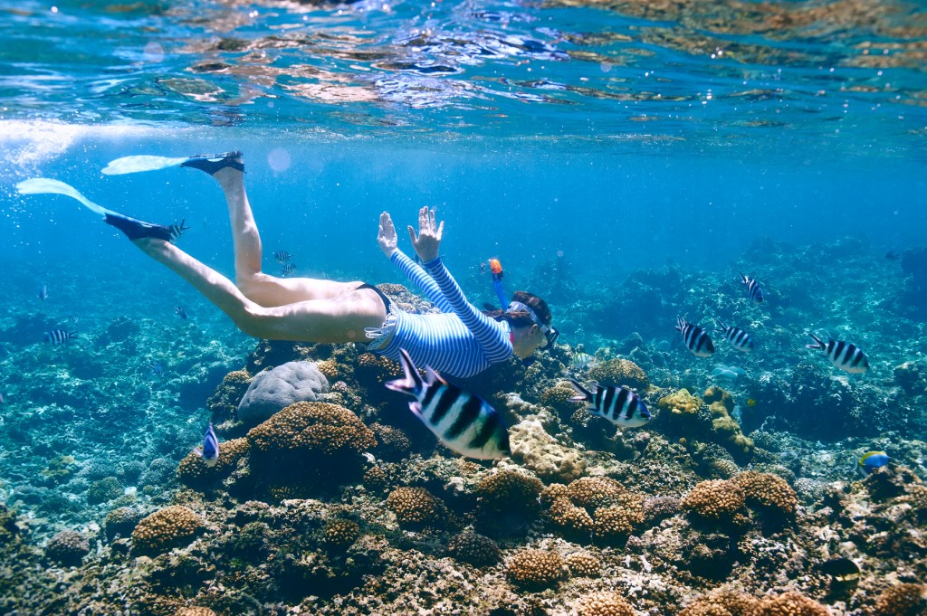 Woman with mask snorkeling in clear water
