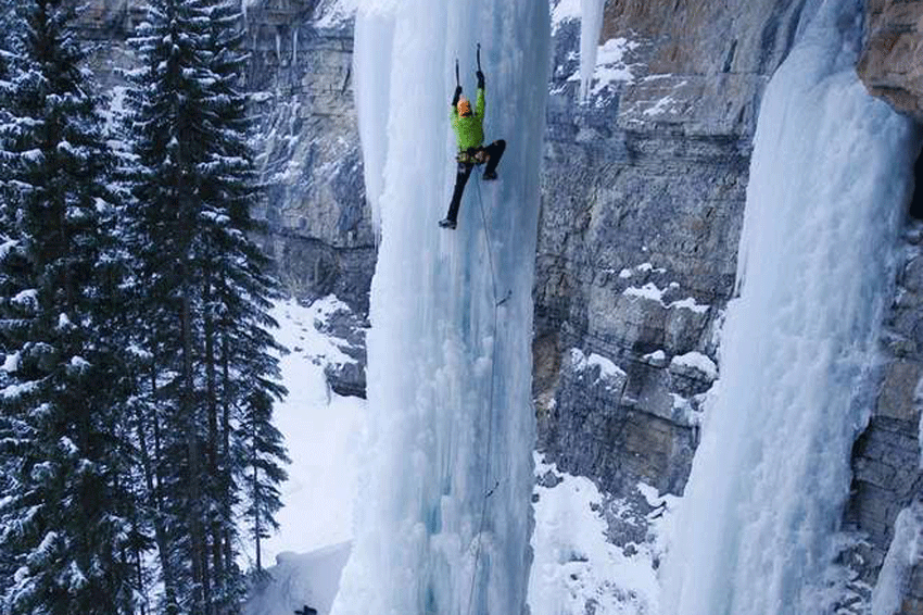 Un homme escalade une cascade gelee l'hiver au Canada